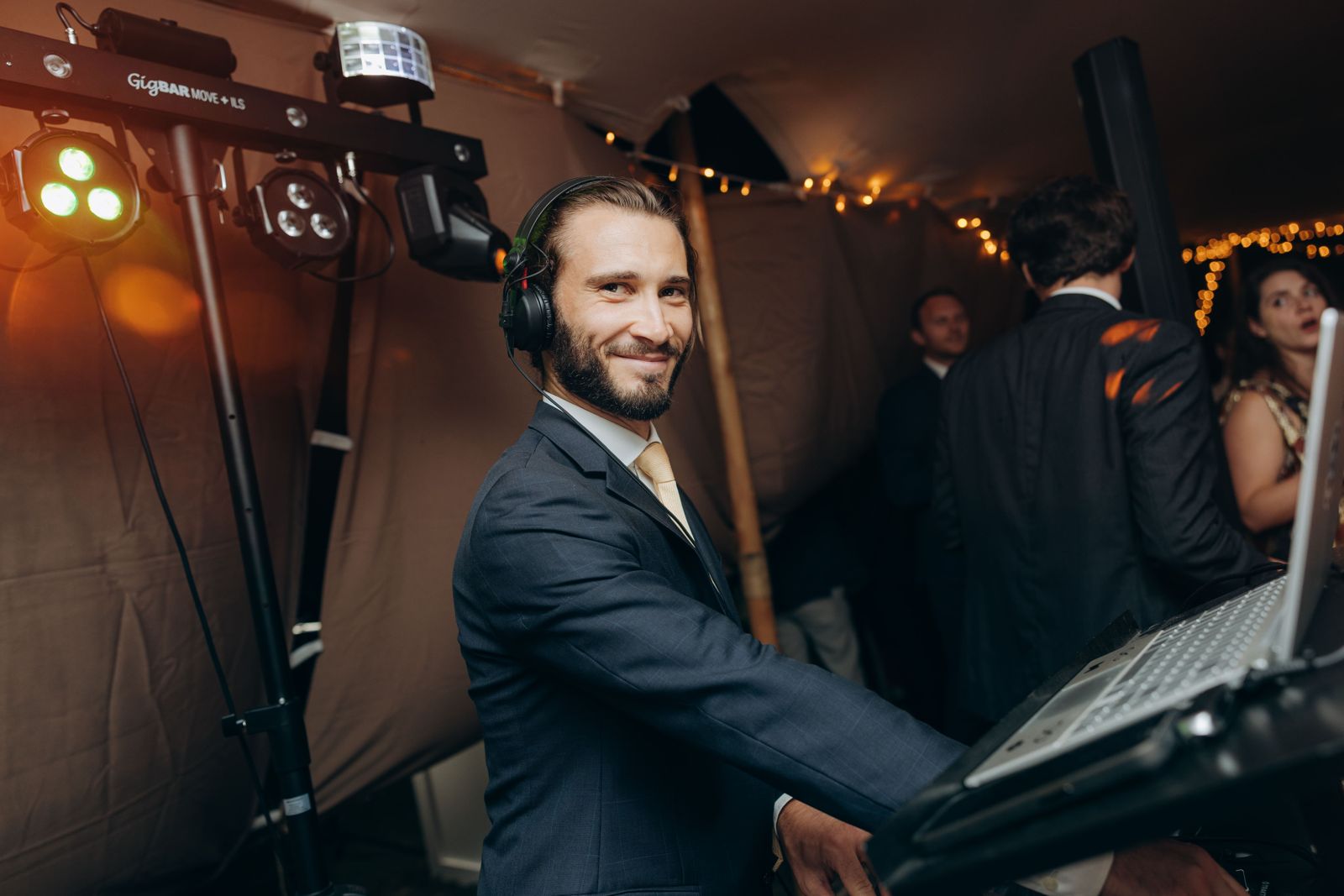 Ferdinand R., DJ de mariage, souriant aux platines sous un barnum, casque sur les oreilles